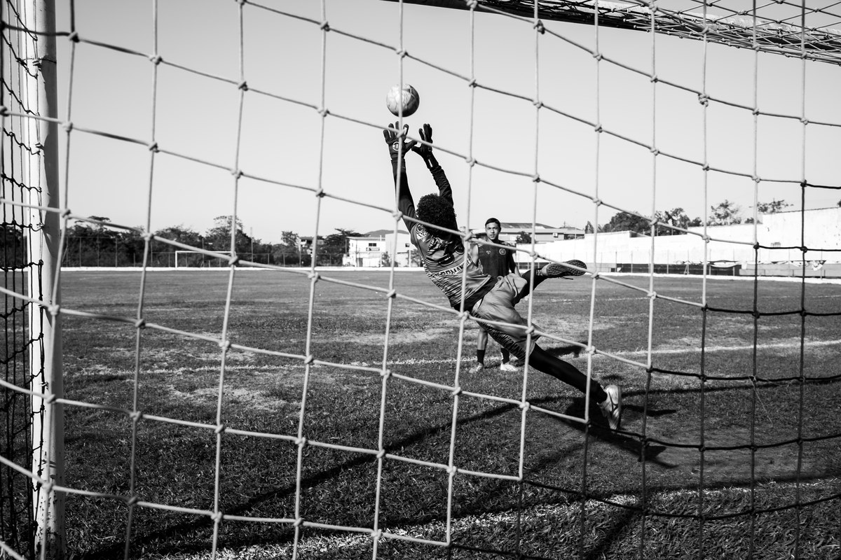 Goleiro em ação durante partida de futebol de várzea no Guarujá